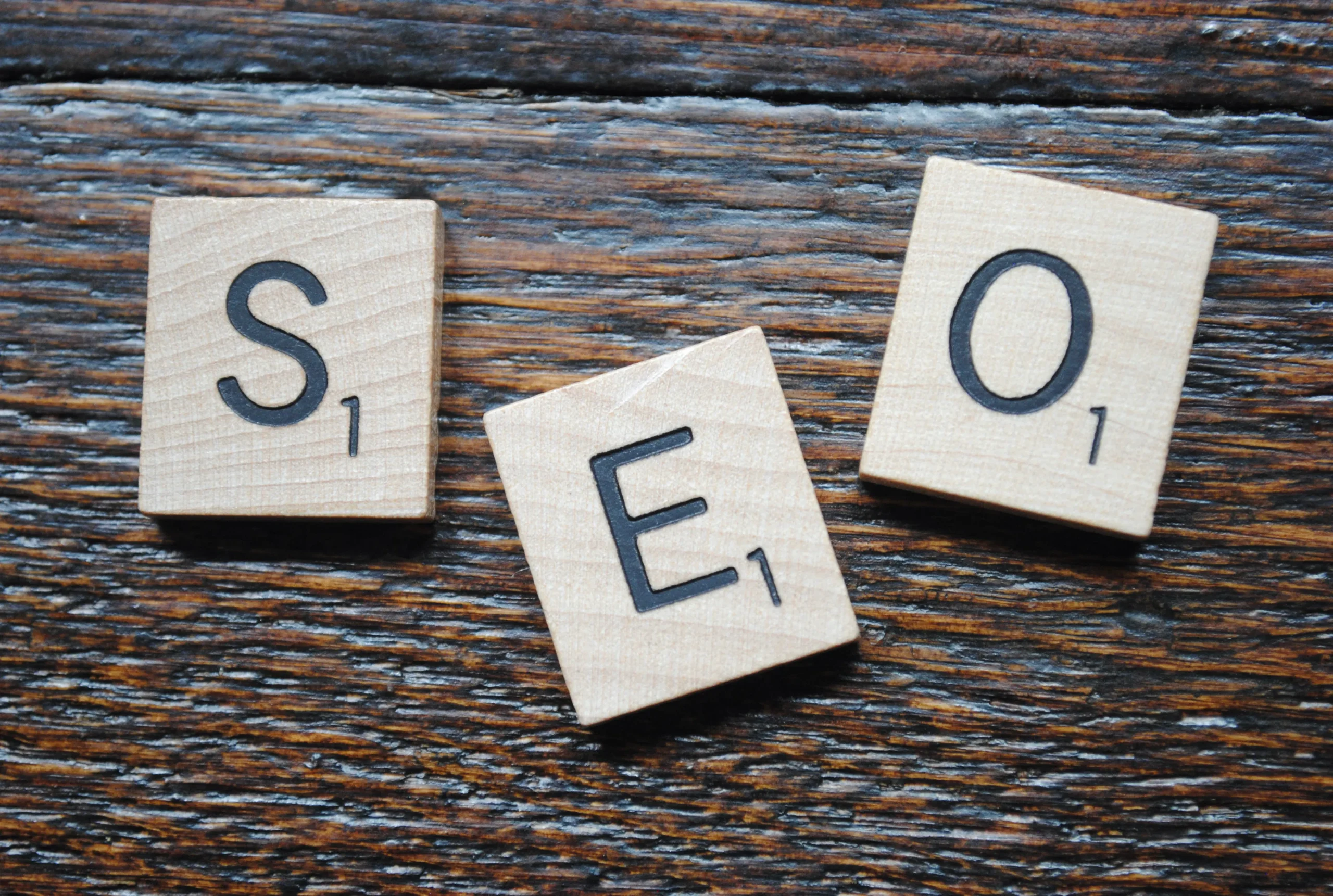 Wooden tiles spelling out 'SEO' on a woodgrain background, symbolizing the importance of AI SEO blog writing for increasing online visibility.