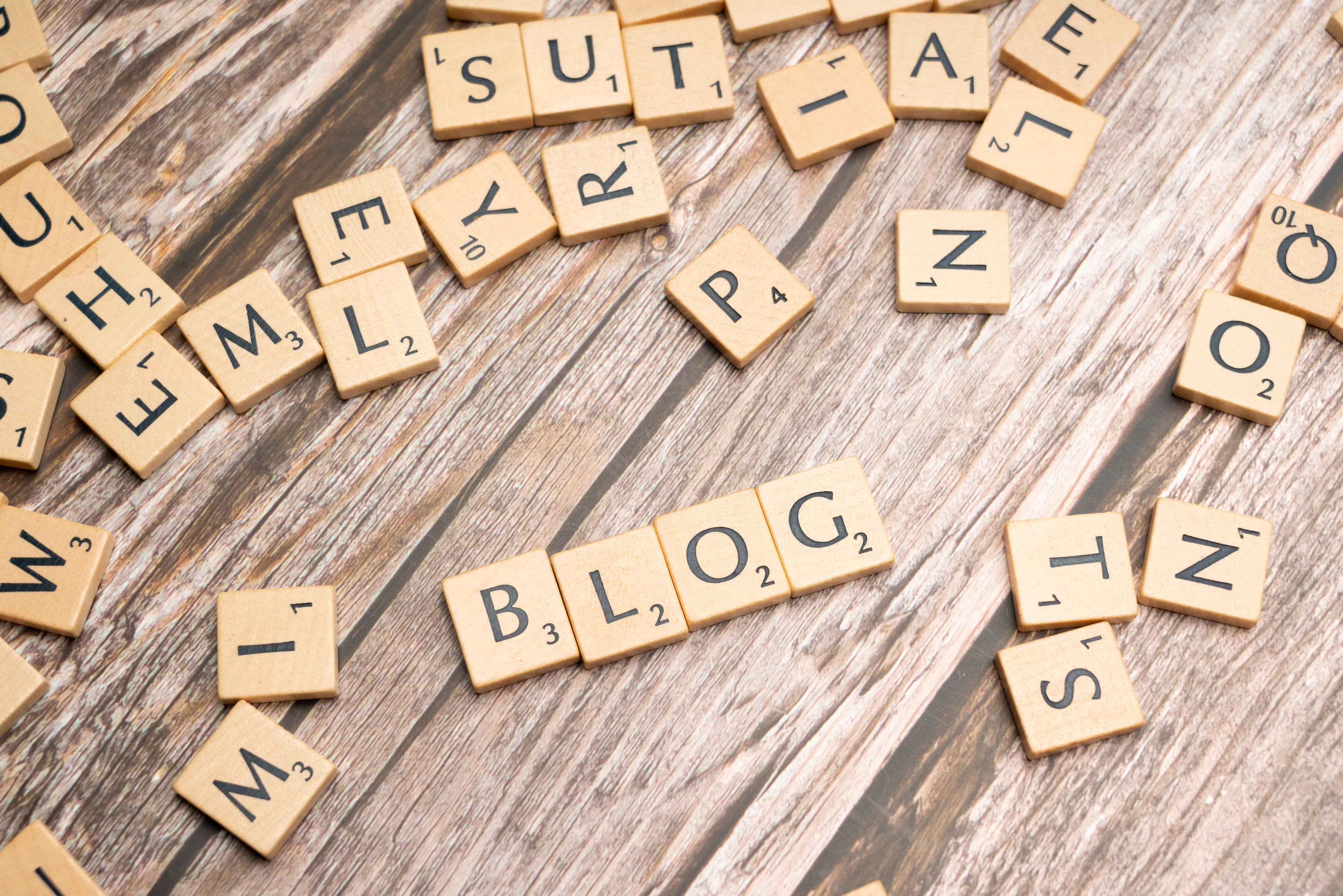 Scrabble tiles spelling out 'BLOG' surrounded by scattered letters, symbolizing the creative process of an AI blog writer aiming to improve search engine optimization and ensure a blog post is noticed.