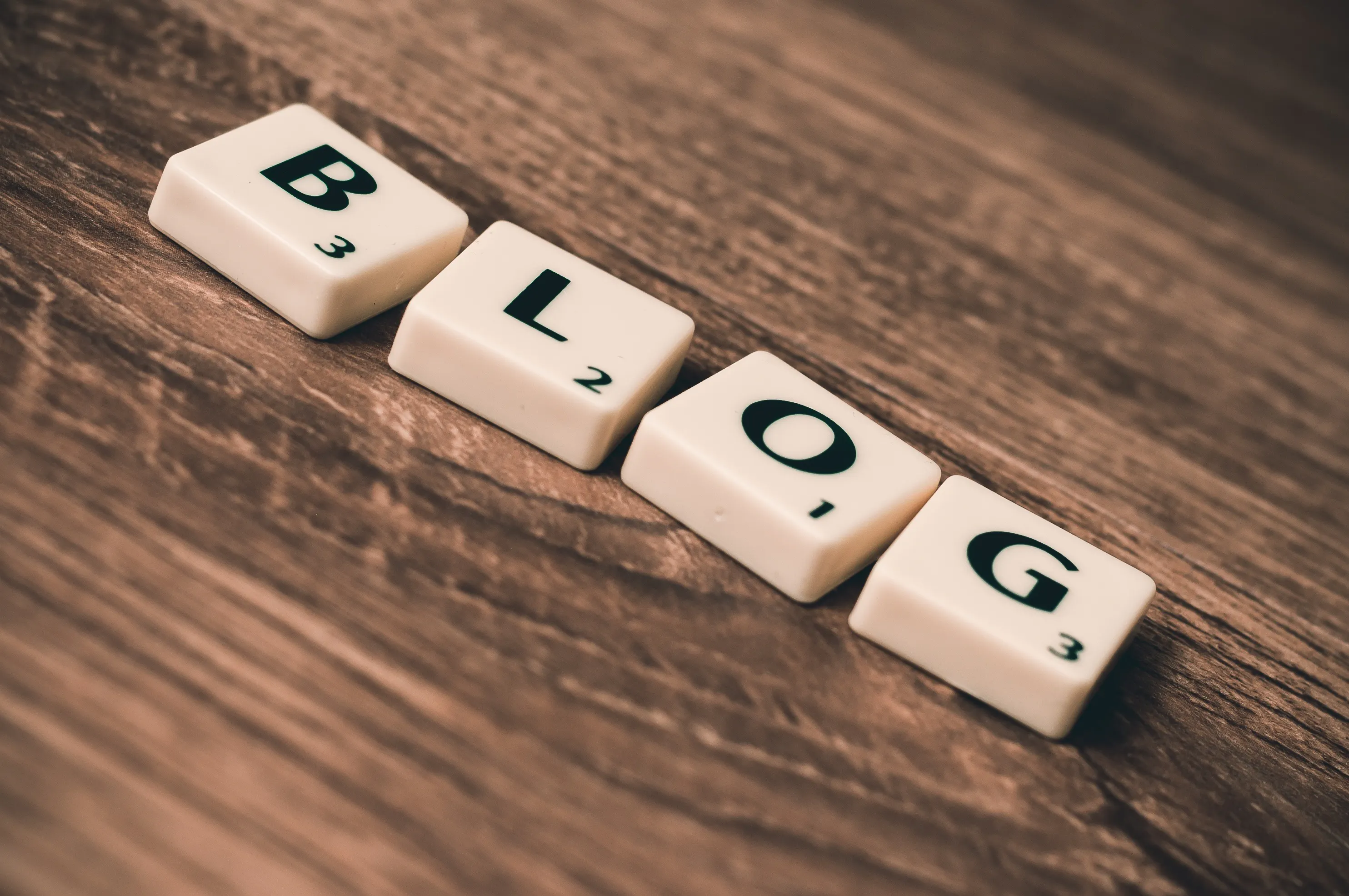 Scrabble tiles spelling 'BLOG' on a wooden surface, representing the concept of blogging and how AI can be used as a blogging tool for AI content creation.