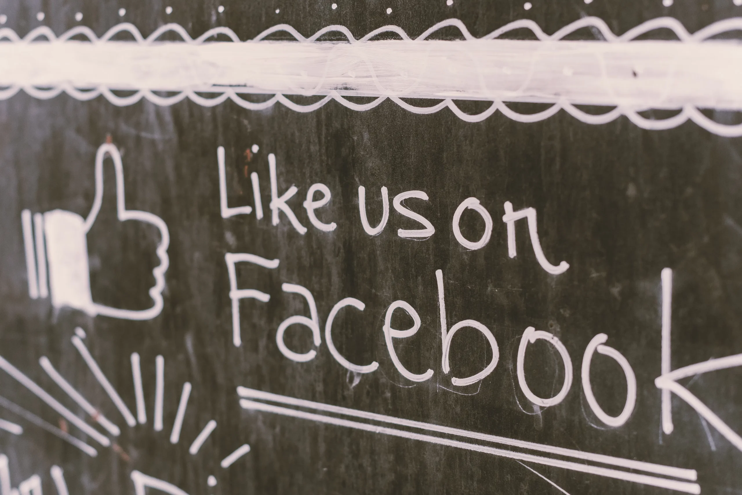 A chalkboard with 'Like us on Facebook' written on it, indicating the importance of social media promotion for blog content created with AI.