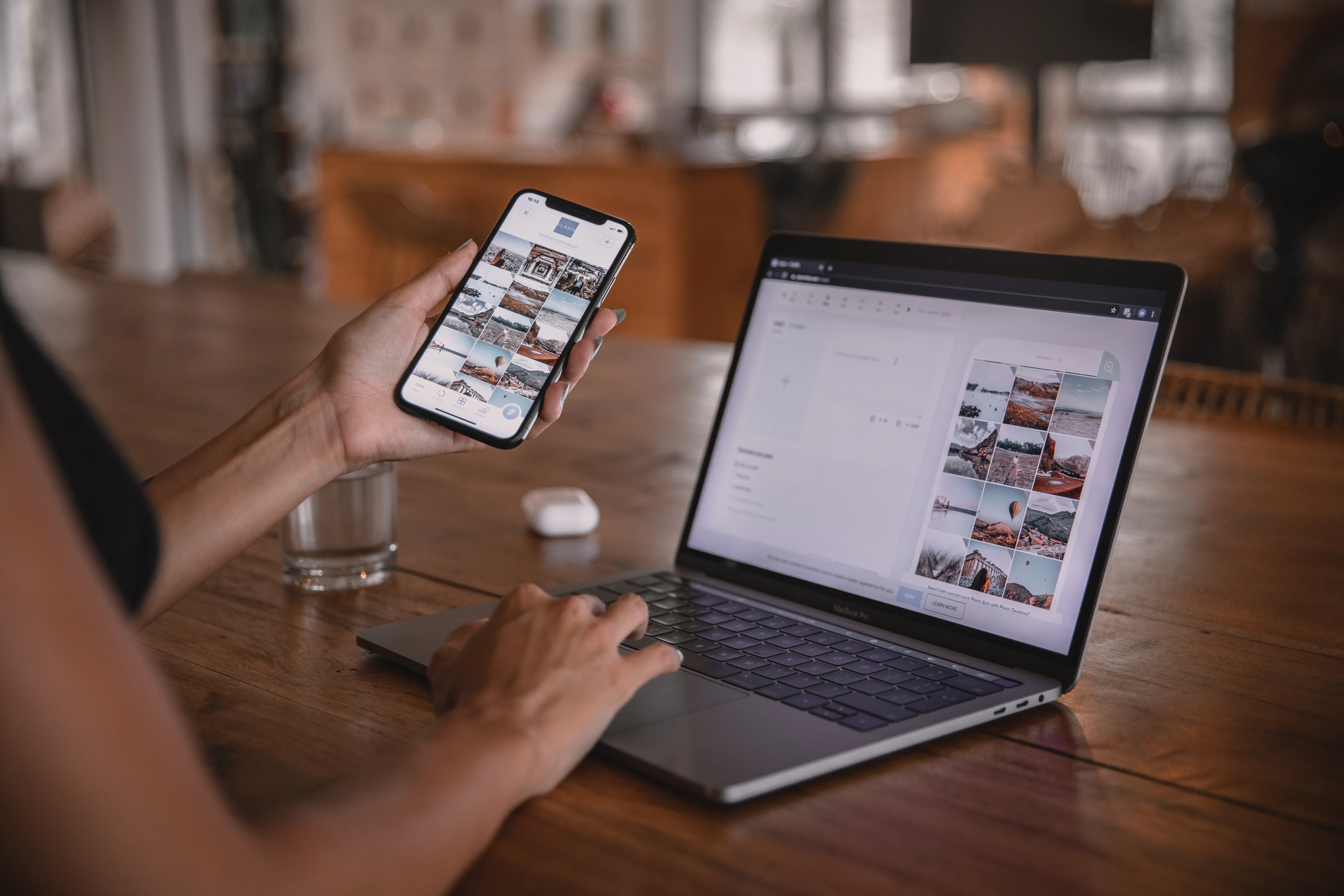 Woman working on a laptop and reviewing images on her phone, representing the process of content creation 2025 and using various blogging tool including AI blog writer to create blog posts.