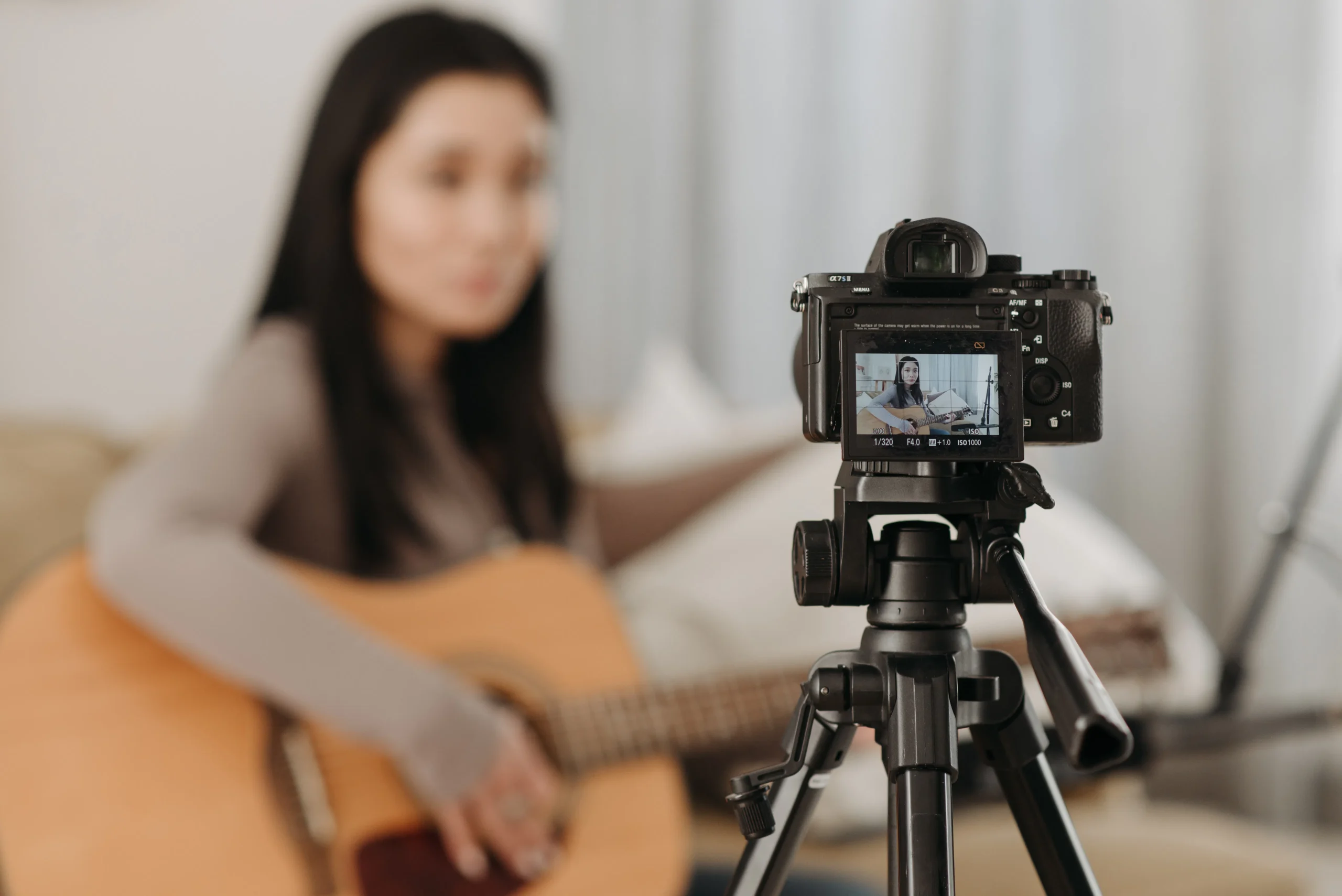 A woman recording herself playing guitar, showcasing the integration of AI tools for content creation 2025 and AI writer, which might include generating music-related blog content.