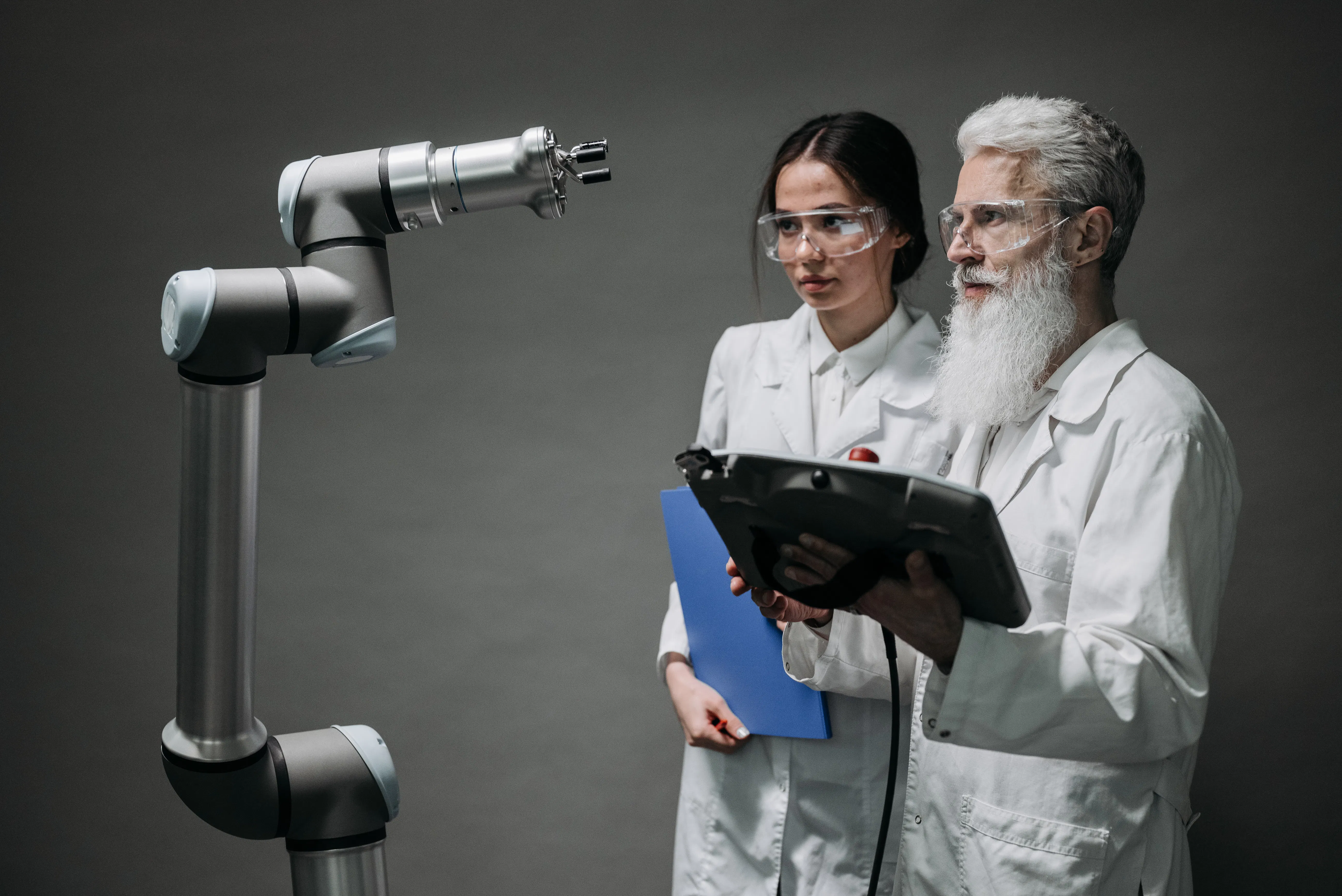 Two scientists in lab coats observing a robotic arm, representing AI-powered content creation or the application of AI in various industries.