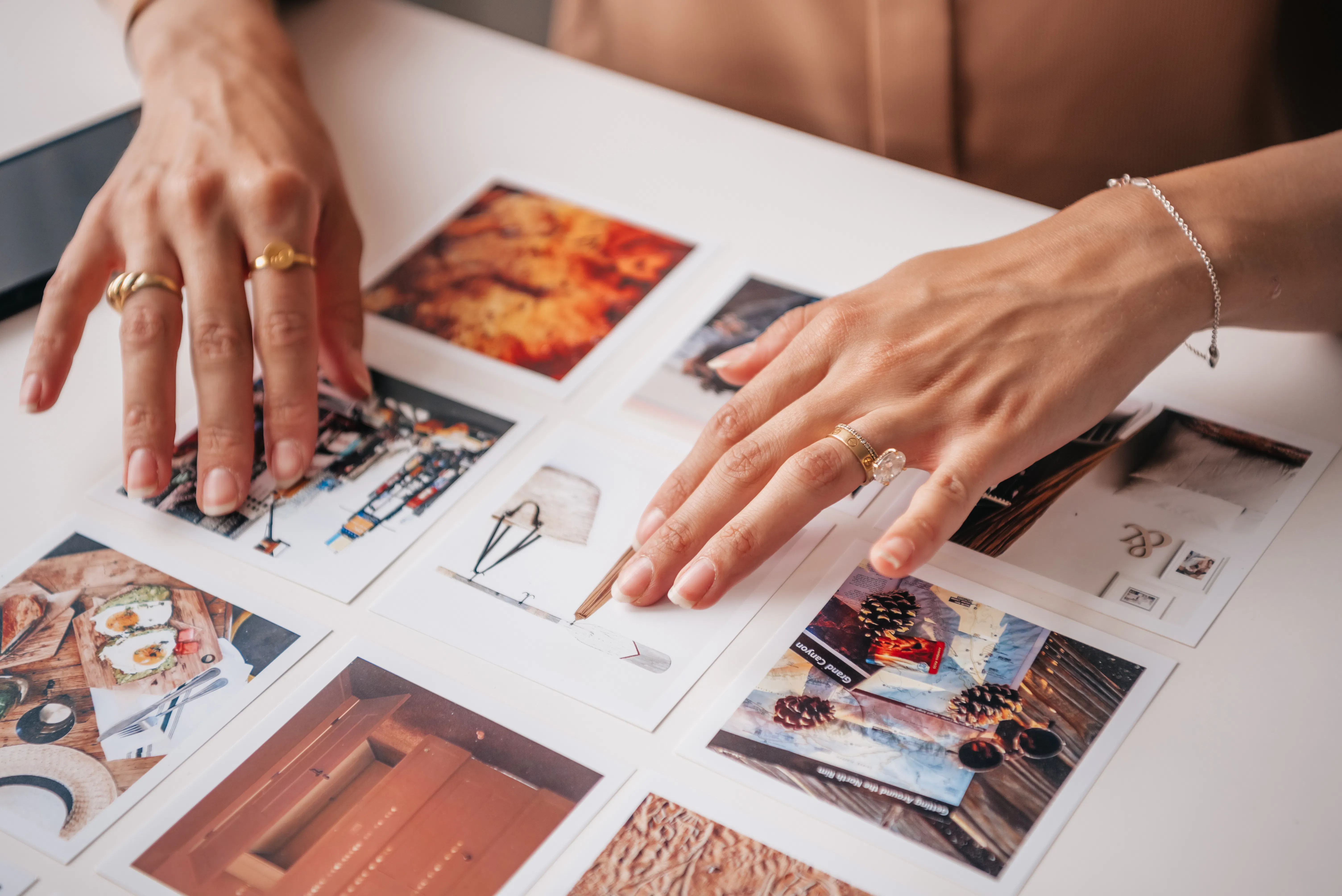 Hands with rings arranging various photographs, representing the curated content creation process that can be enhanced by an AI writing assistant for blogs.