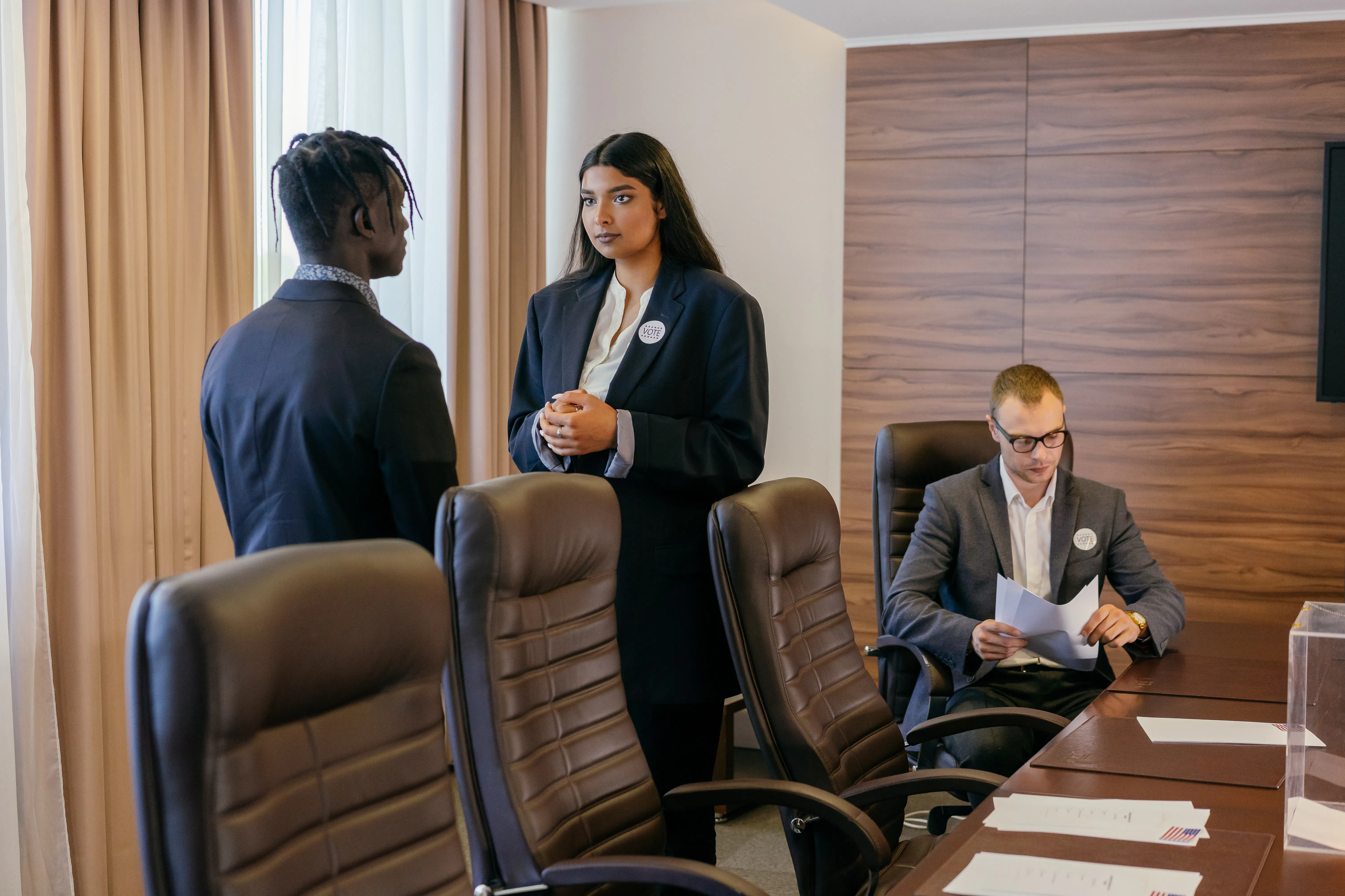Three businesspeople in suits having a discussion in a conference room.