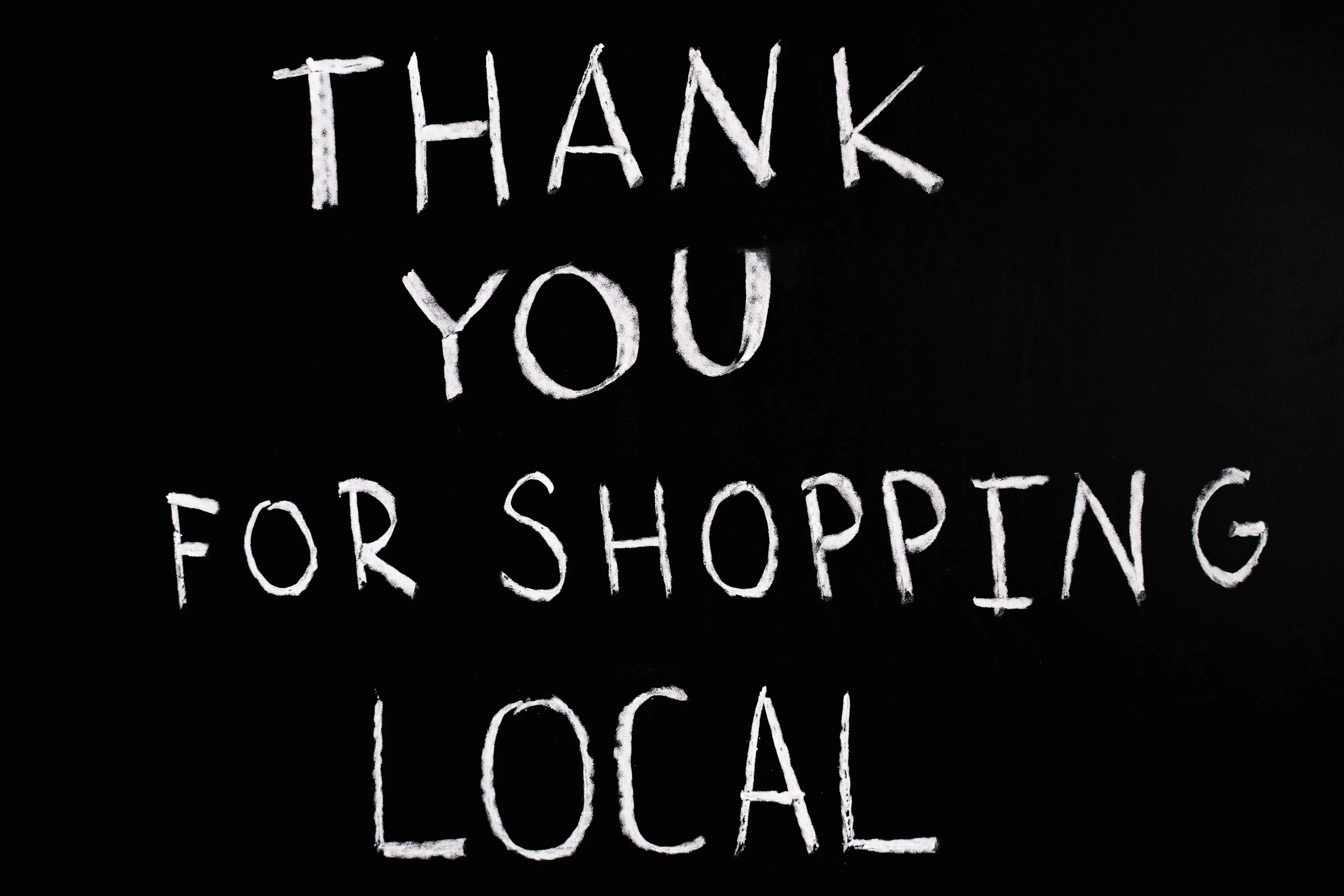 "Thank you for shopping local" written in white chalk on black background