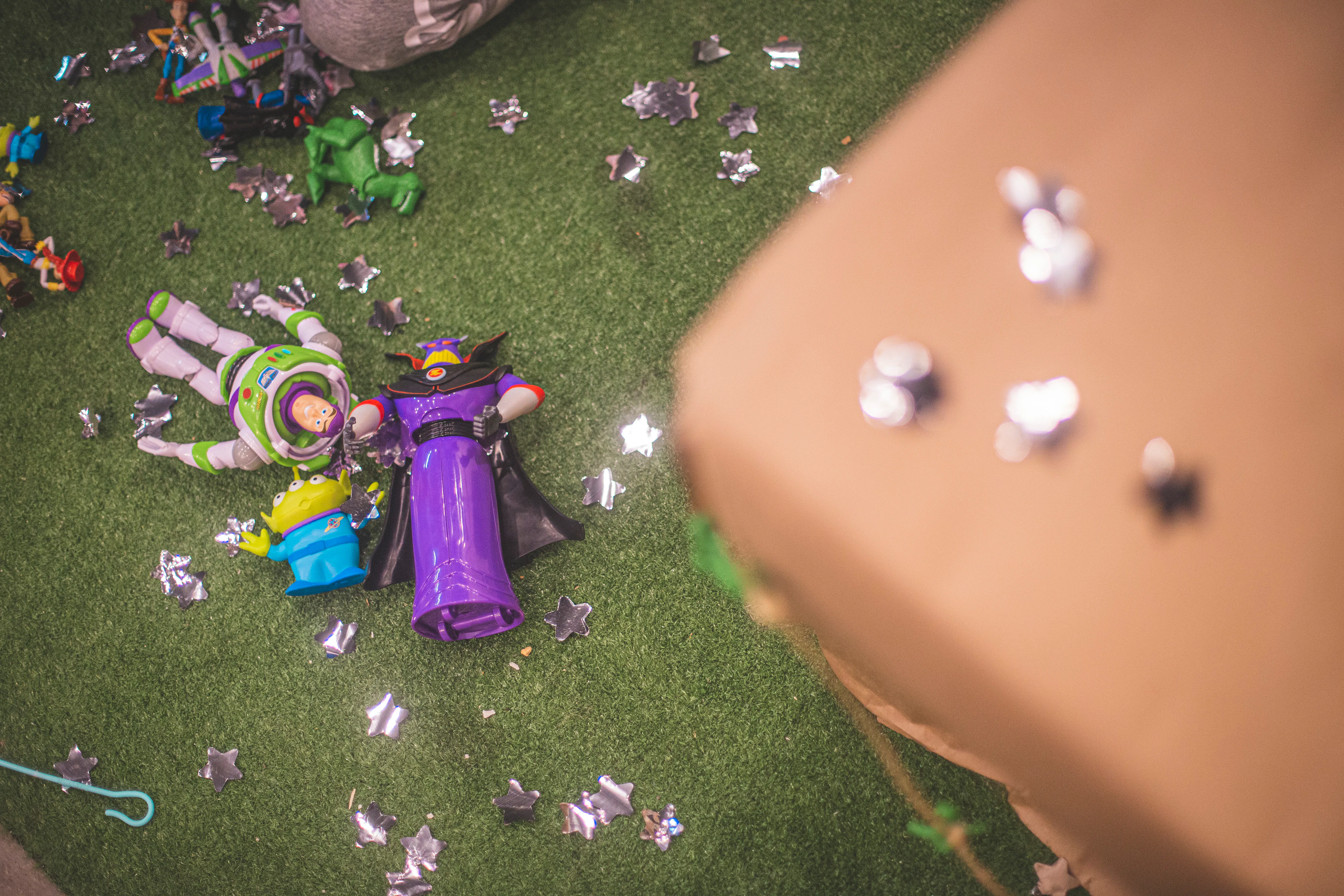 Toy Story action figures scattered on artificial grass with star-shaped confetti.