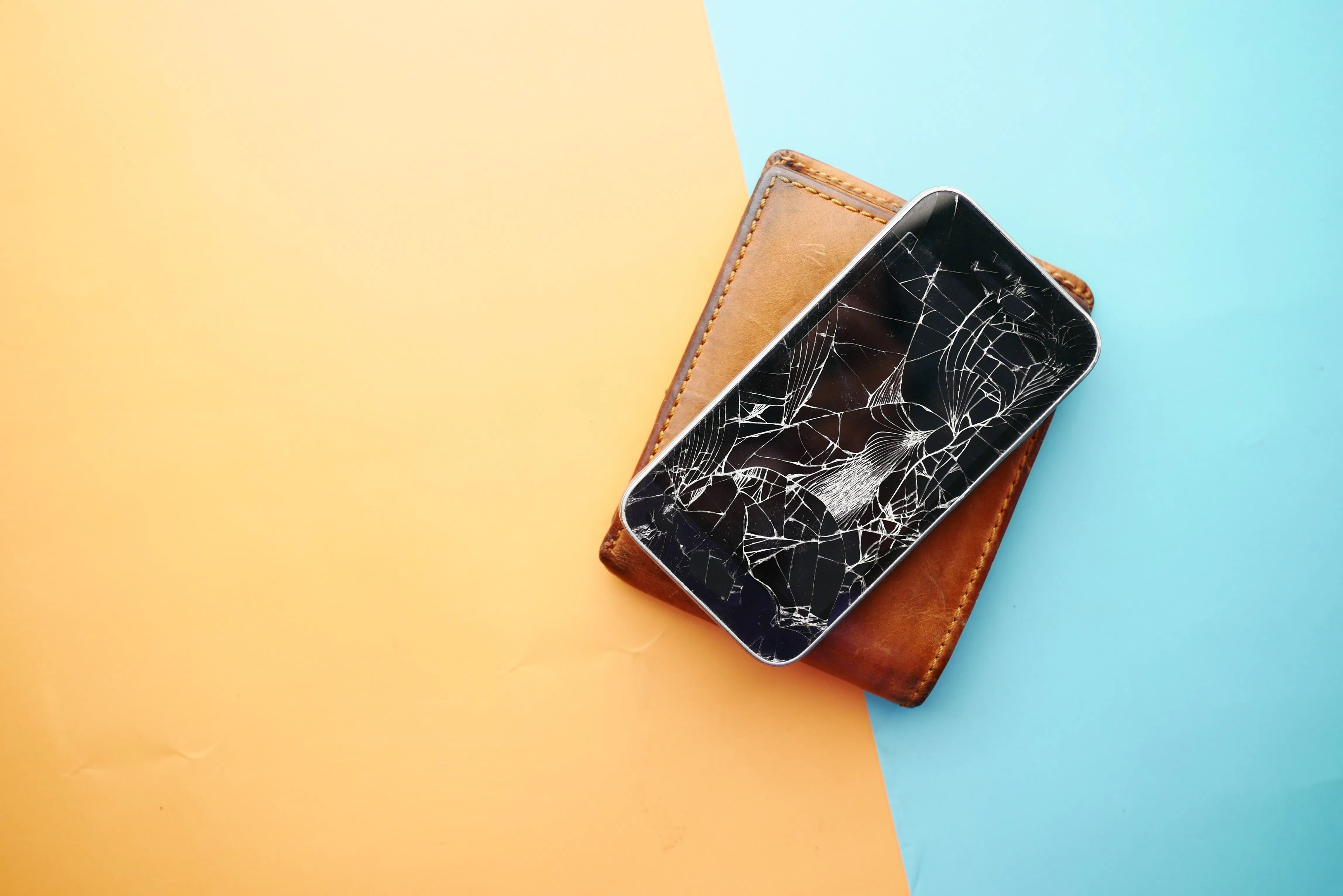 A broken smartphone on a leather wallet, representing errors from an automated content generator.