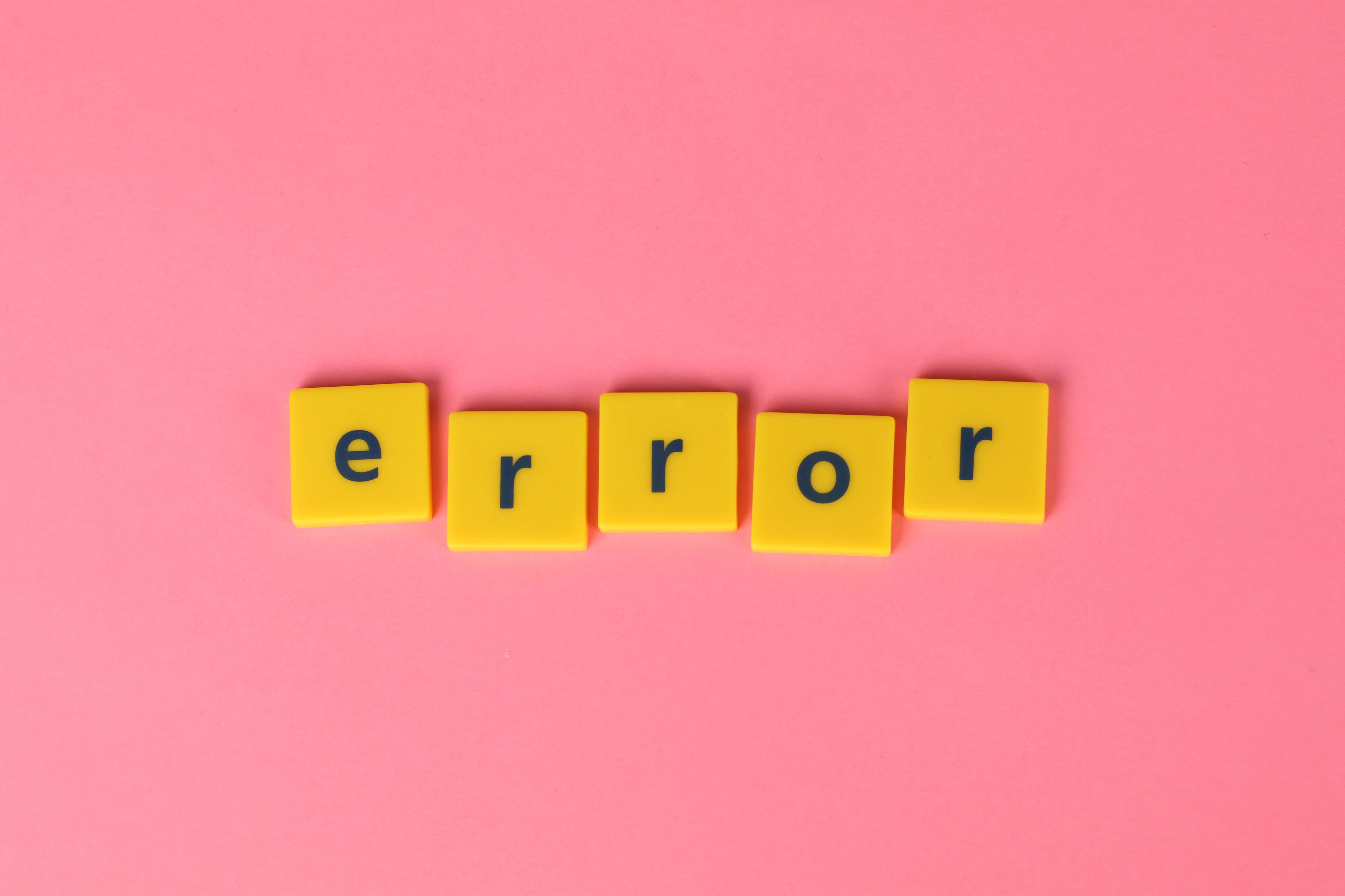 Yellow letter tiles spelling 'error' on a pink background, symbolizing AI writing limitations and where AI copywriting software fails.