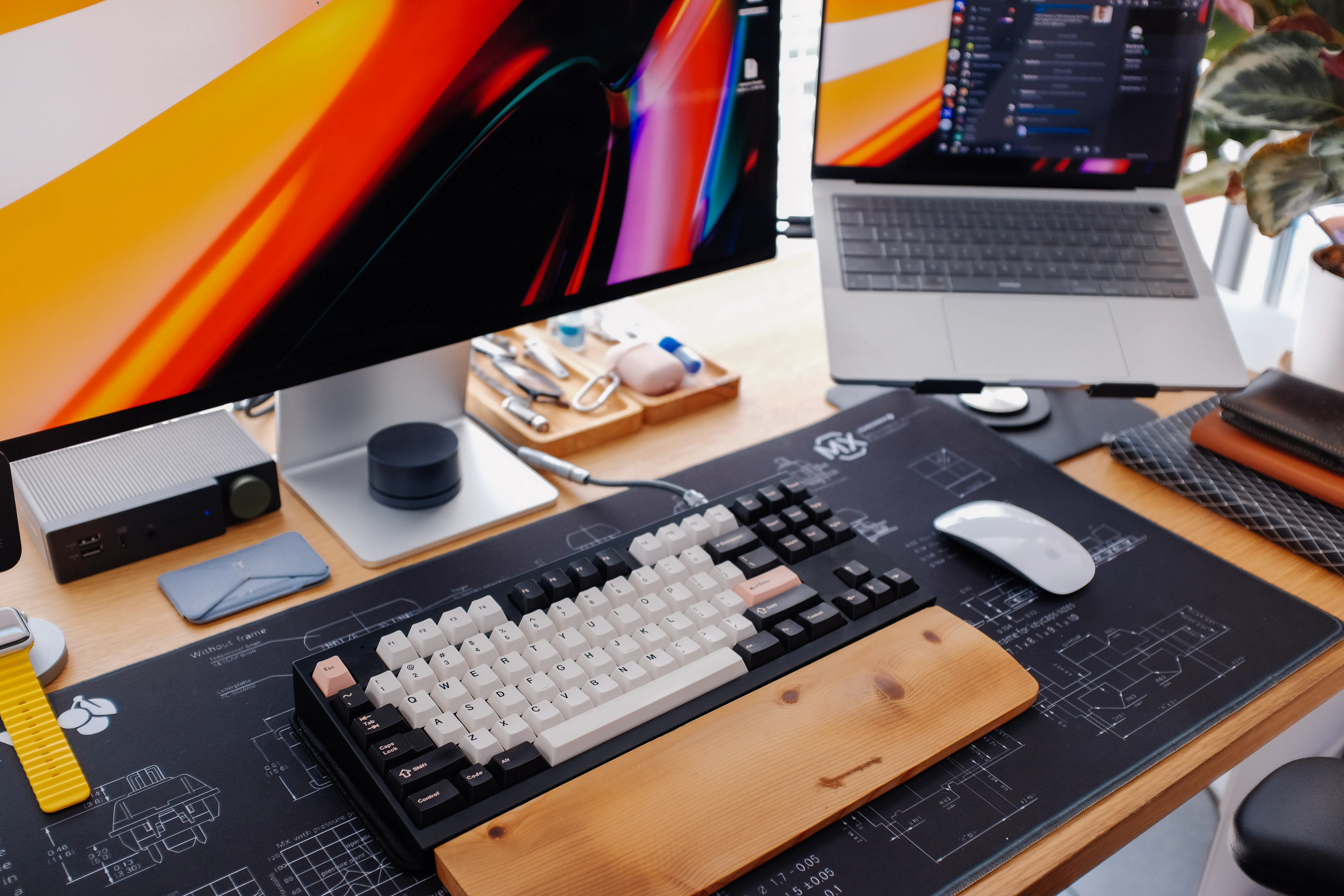 Modern desk setup with a large monitor, silver MacBook, and custom mechanical keyboard, ideal for using an AI writing assistant or copywriting software.