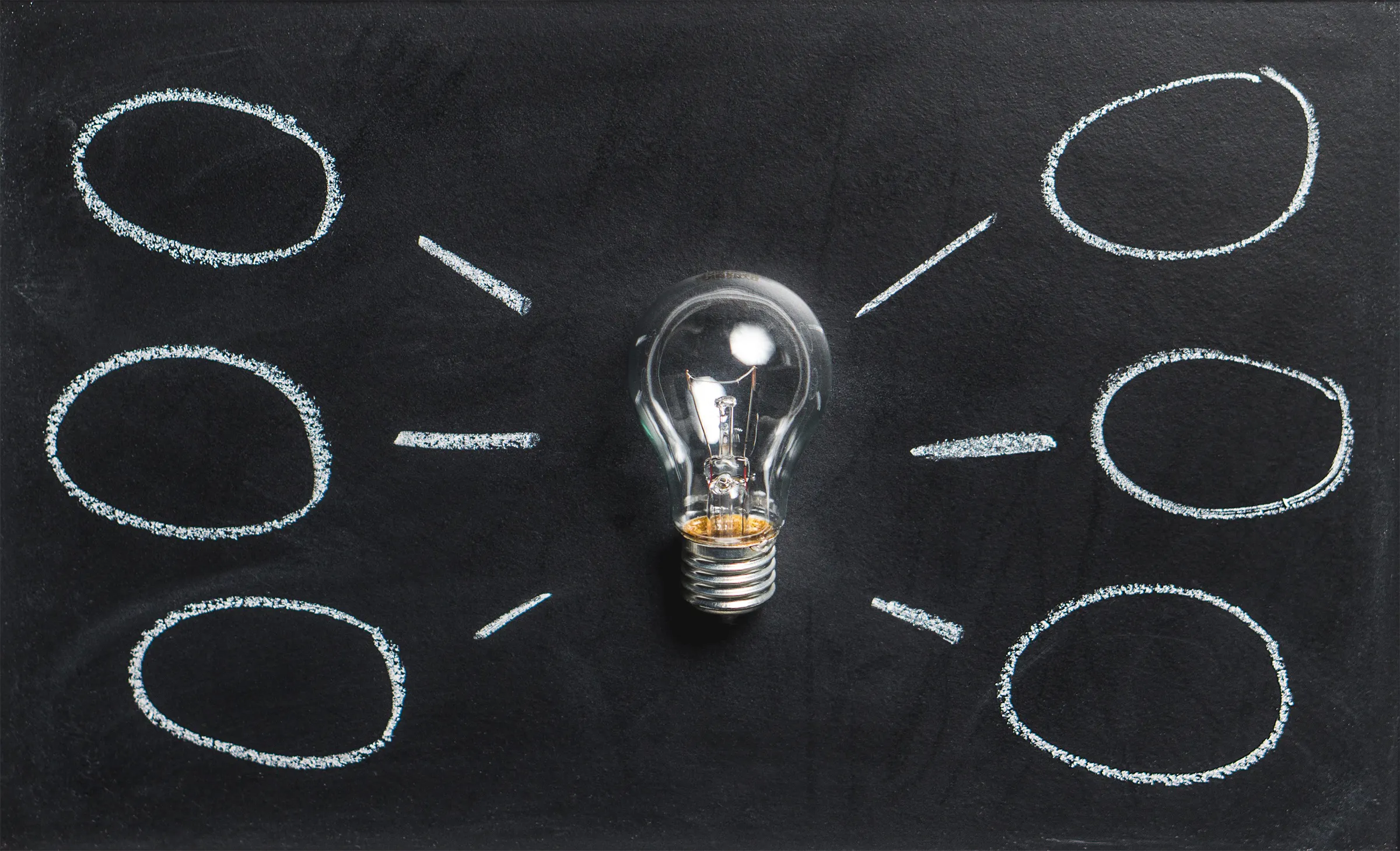 A lightbulb on a chalkboard with drawn circles, representing AI content workflow and creative ideas.