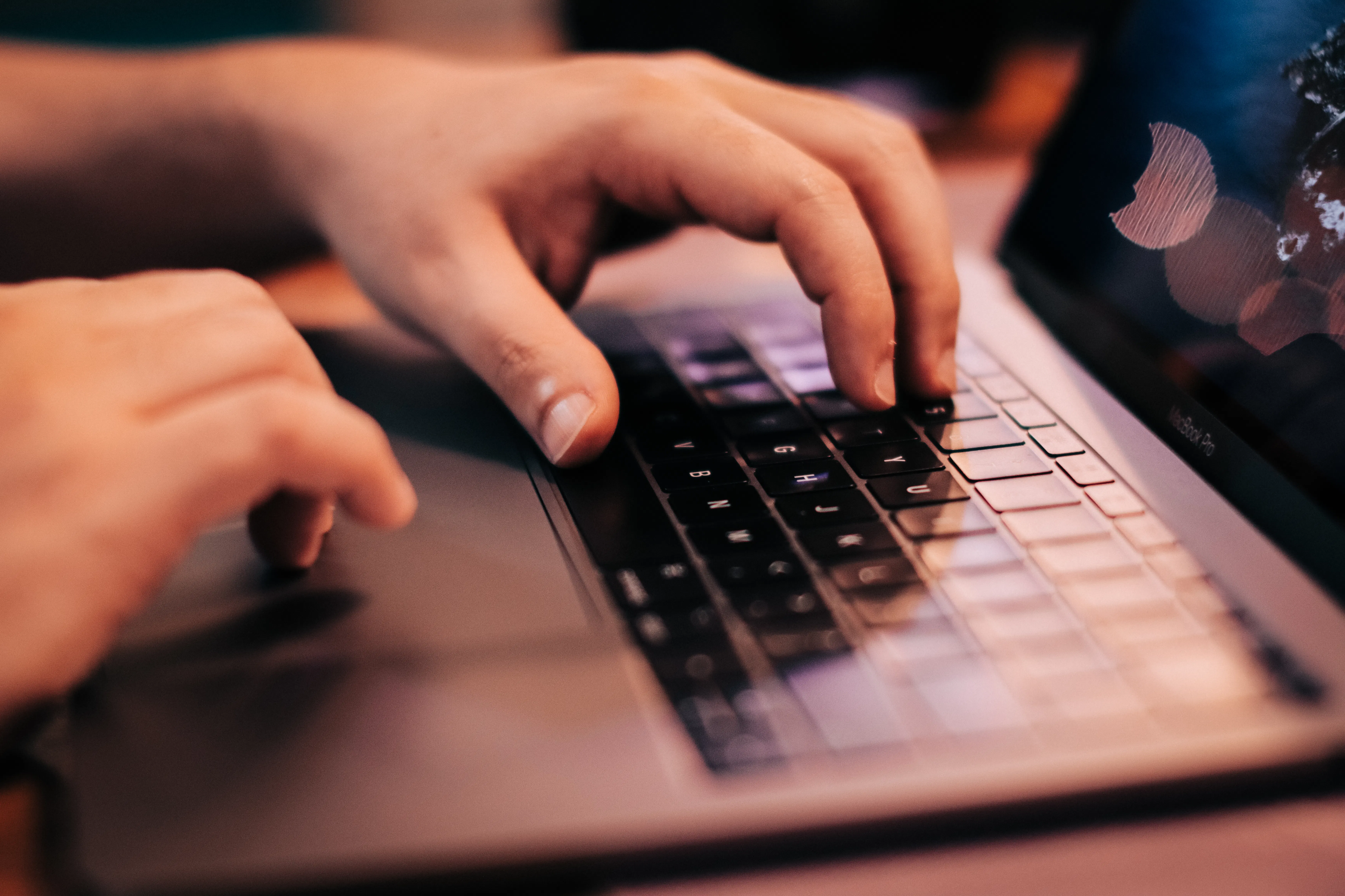 Close-up of hands typing on a laptop, using an AI writing tool for safe content automation.