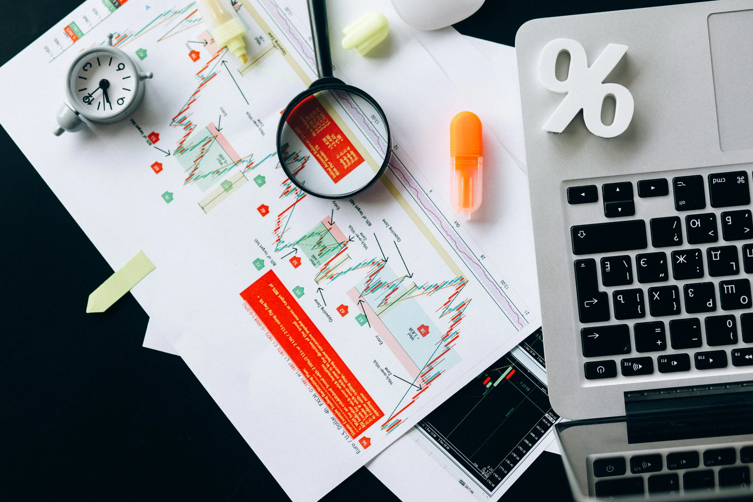 Top-down view of financial charts, laptop, and tools for analyzing seo content automation and metrics.