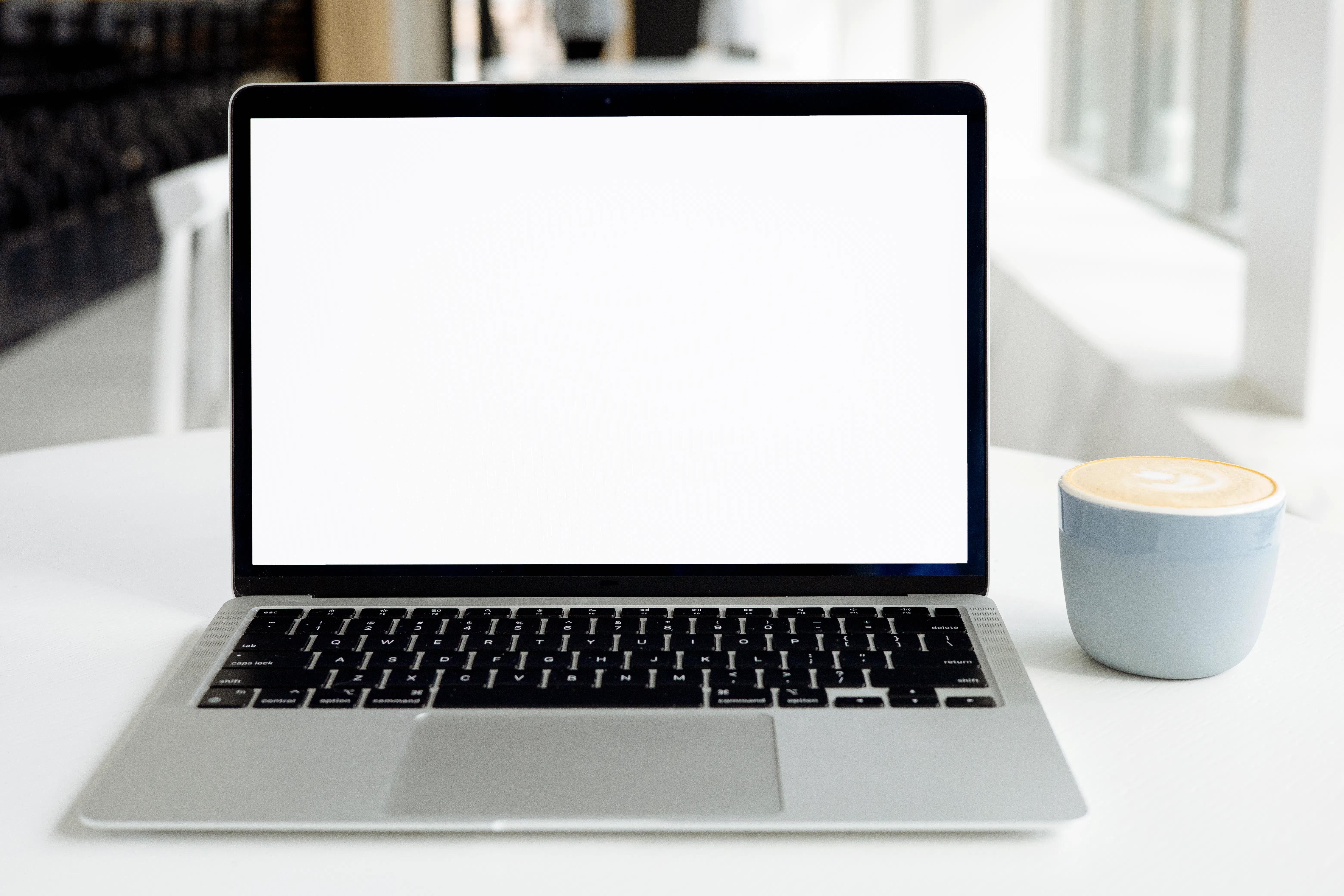 A laptop with a blank screen next to coffee, perfect for using an AI content writer to draft articles.