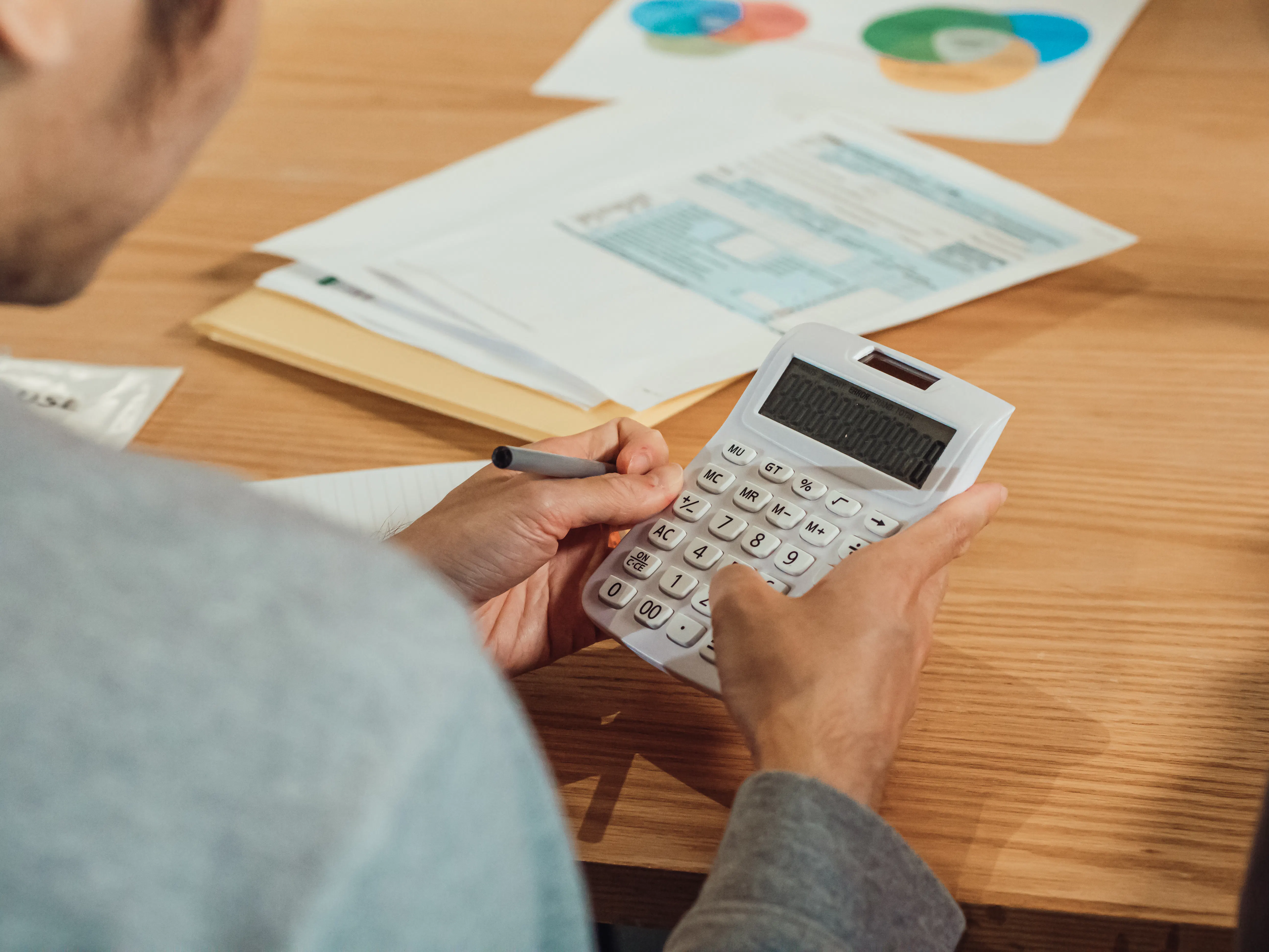 Person using a calculator to compare costs of paid vs free ai writers.