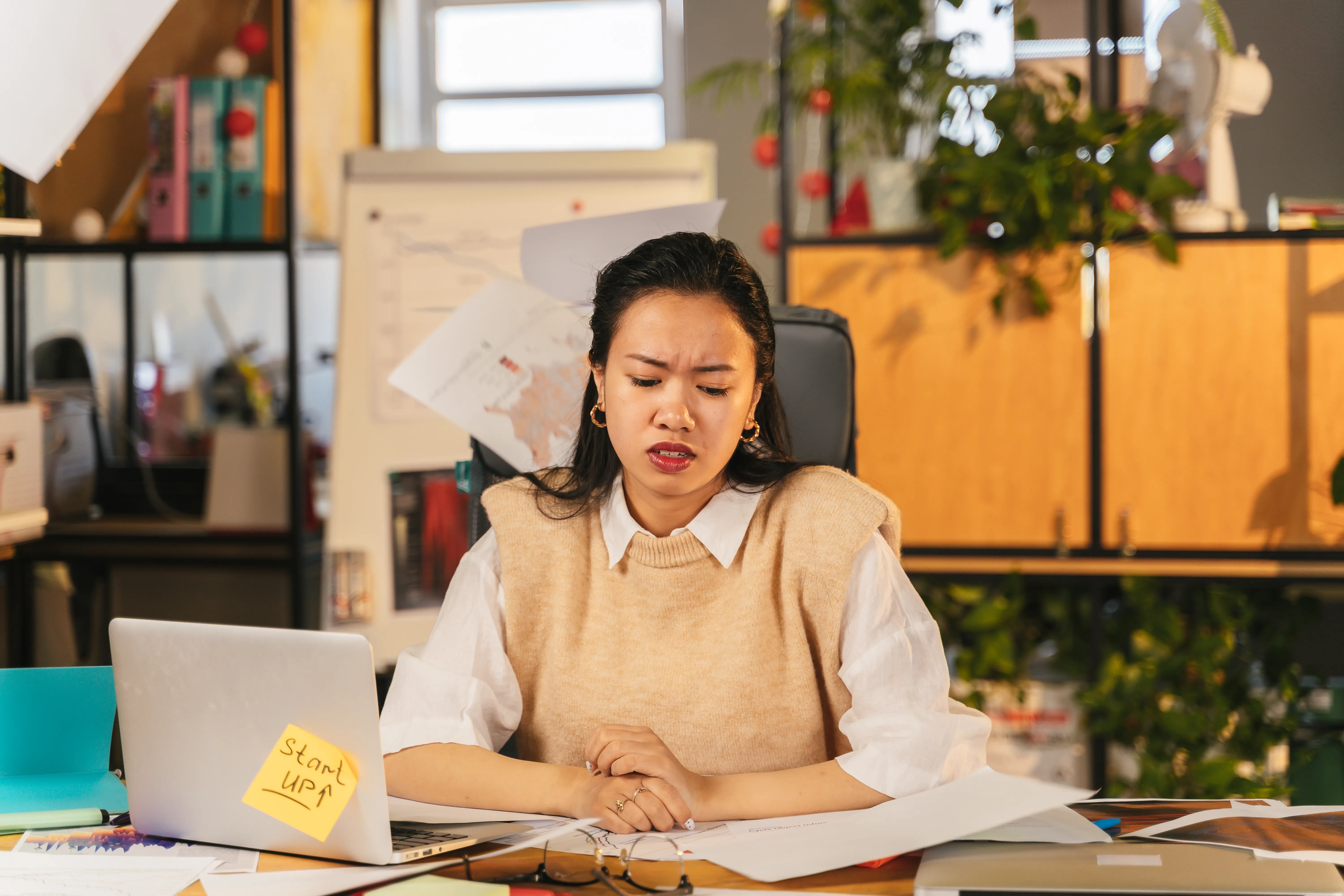 A stressed woman looking at a laptop, highlighting the challenges of search engine optimization for AI.