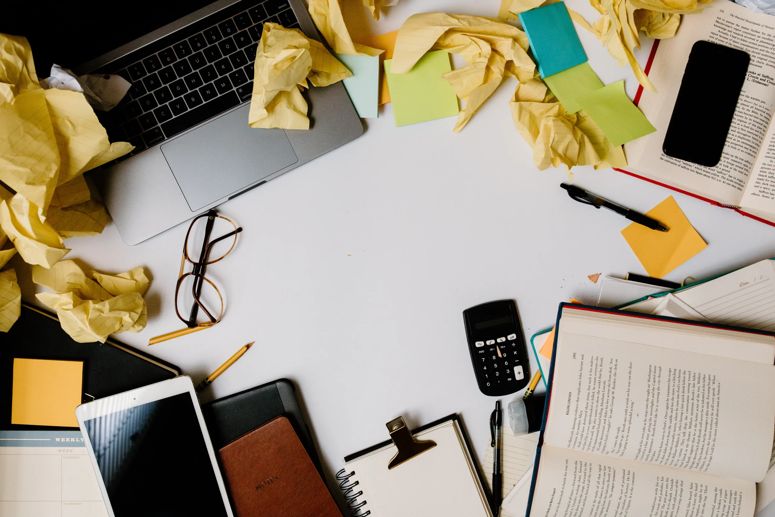 Cluttered desk with laptop and notes for seo content generator tool analysis.