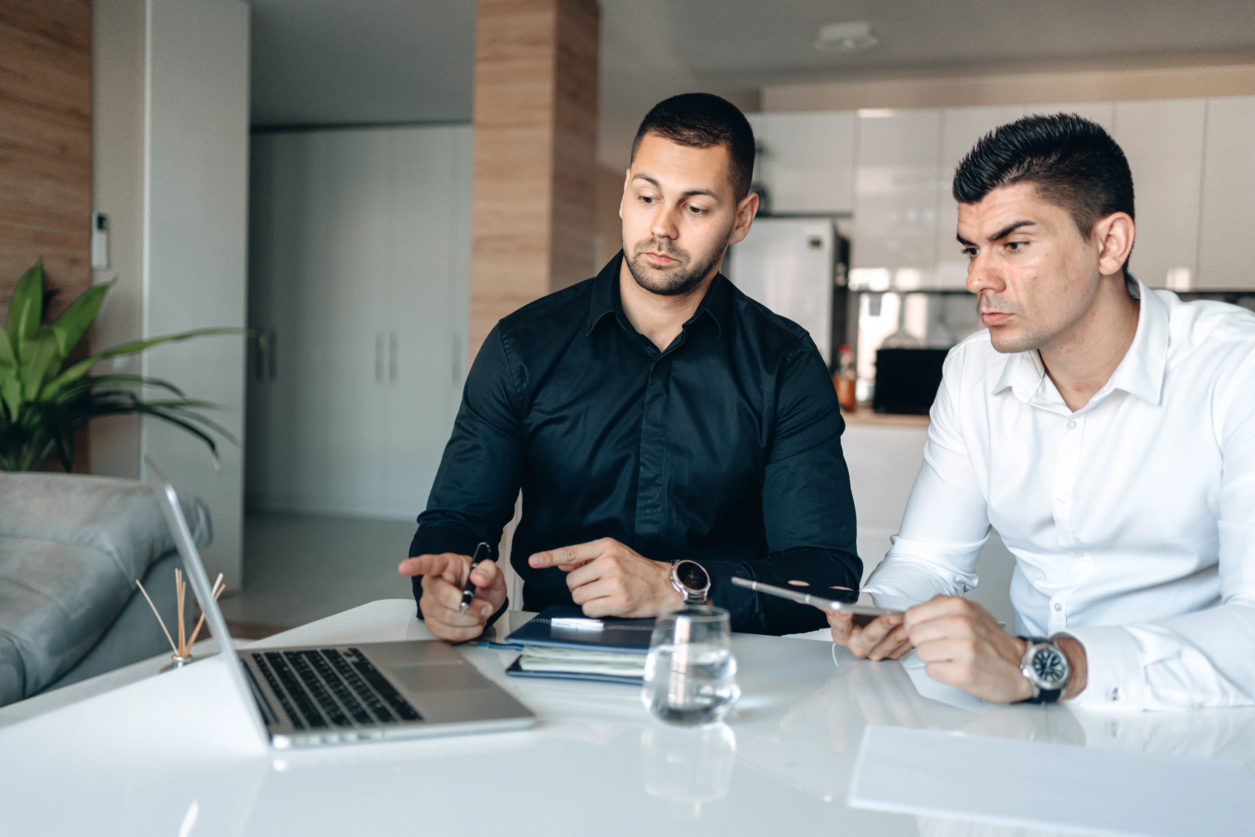 Two businessmen collaborating on a generative engine optimization strategy using a laptop in an office.