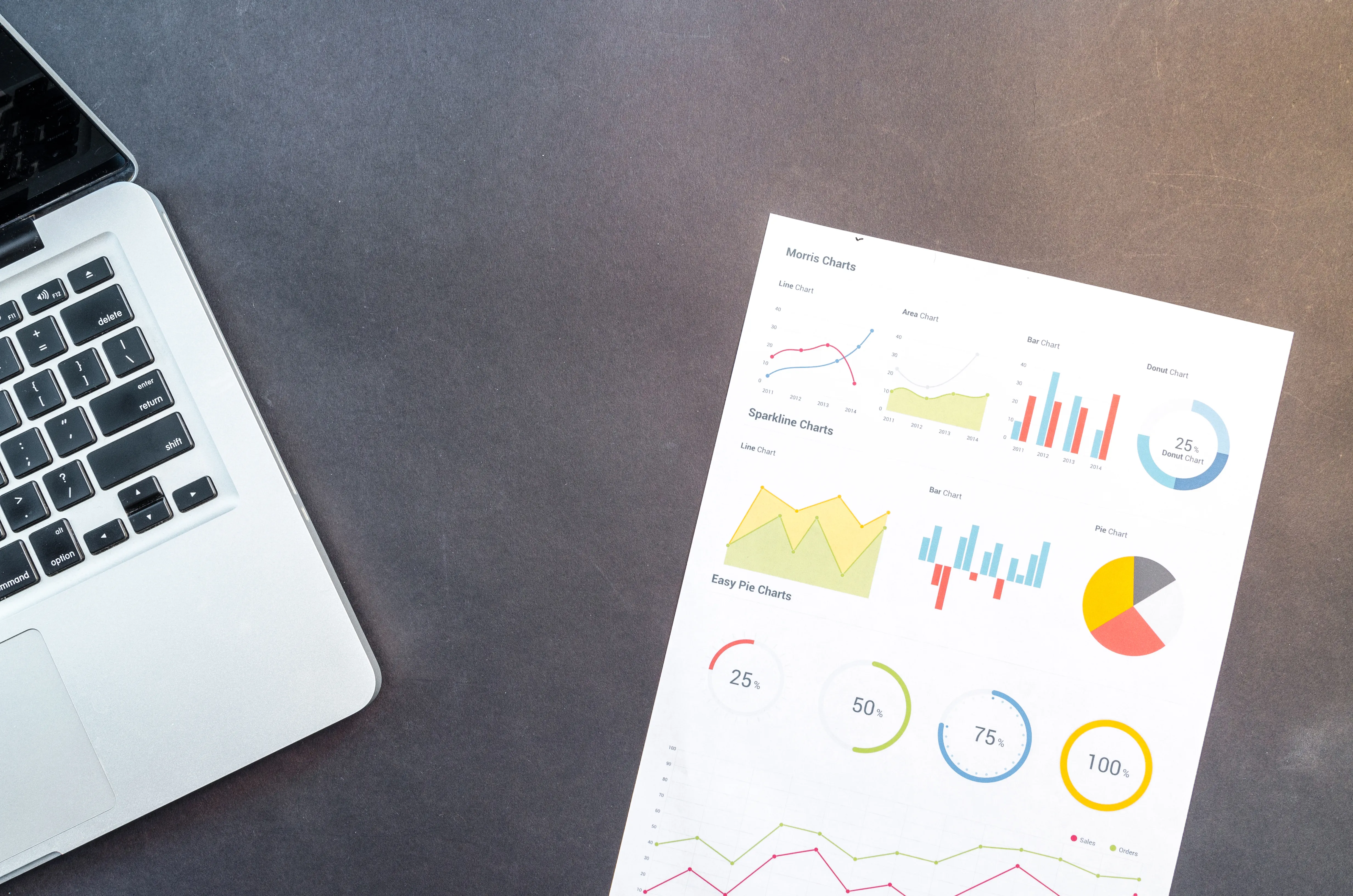 Laptop next to printed charts, demonstrating data organization for AI answer engine SEO and ranking in AI overviews.