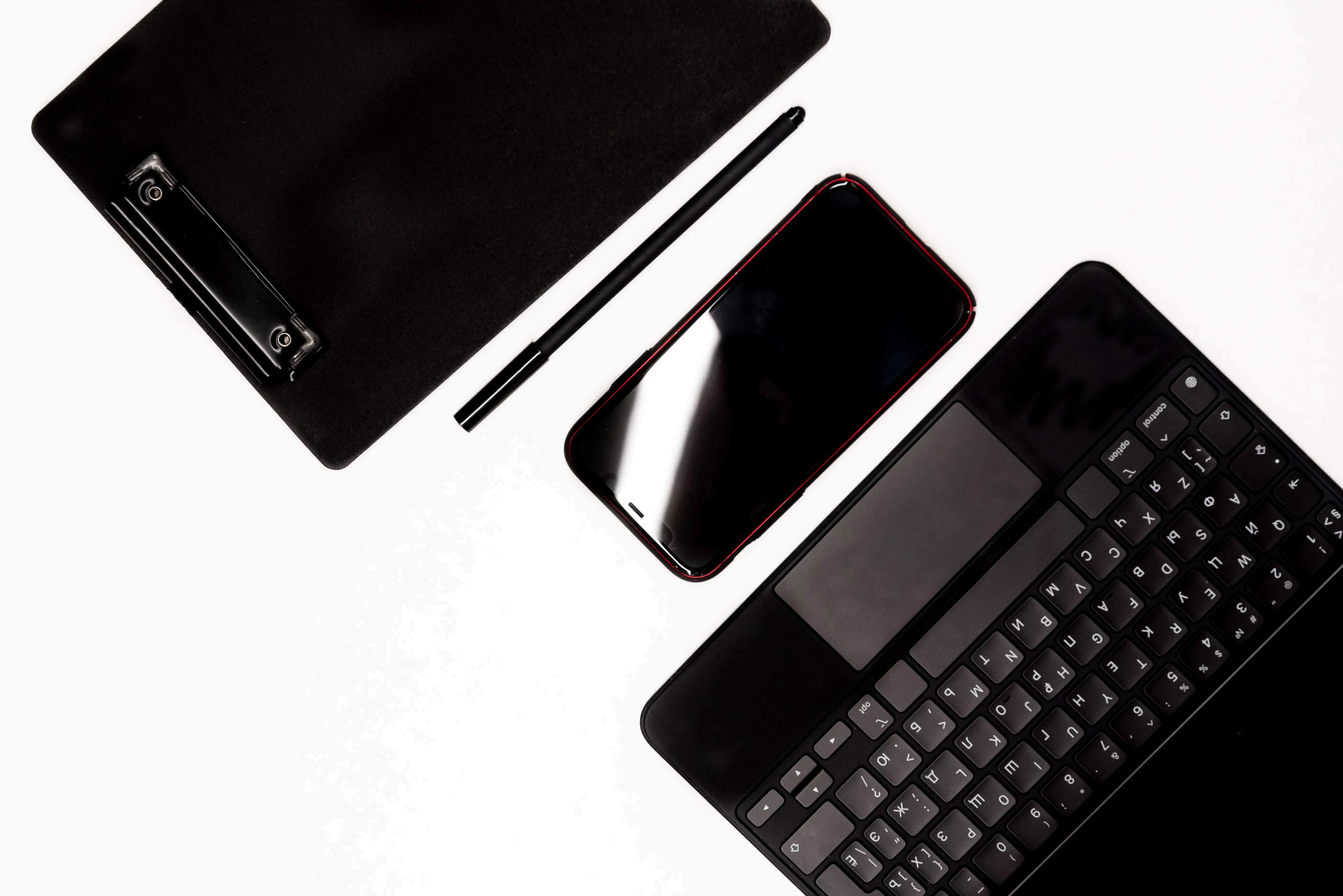 Flat lay of modern gadgets and a clipboard on a white surface, representing tools used for automated seo strategy.