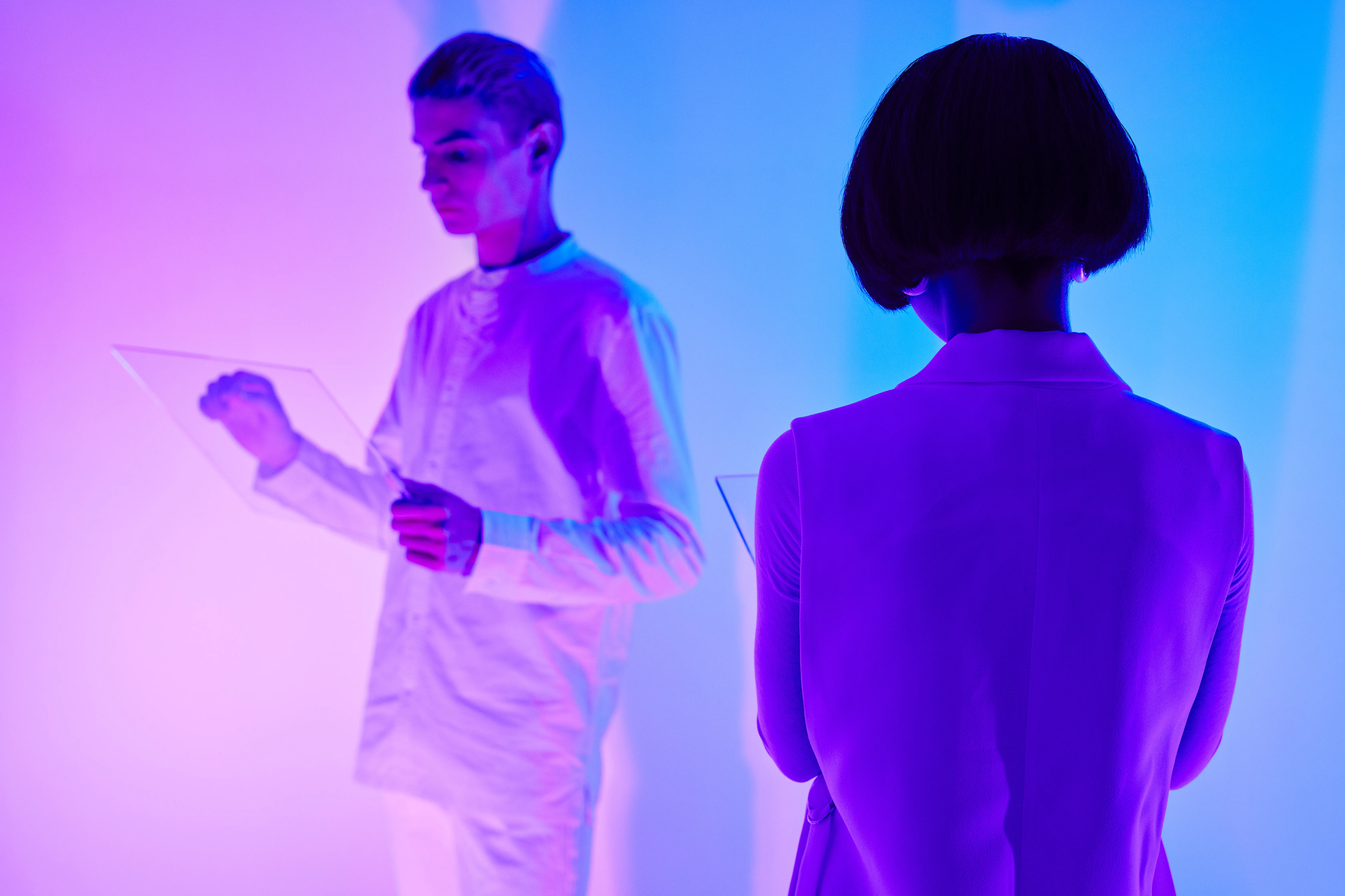 People interacting with glass tablets under blue and pink light, illustrating generative engine optimization.