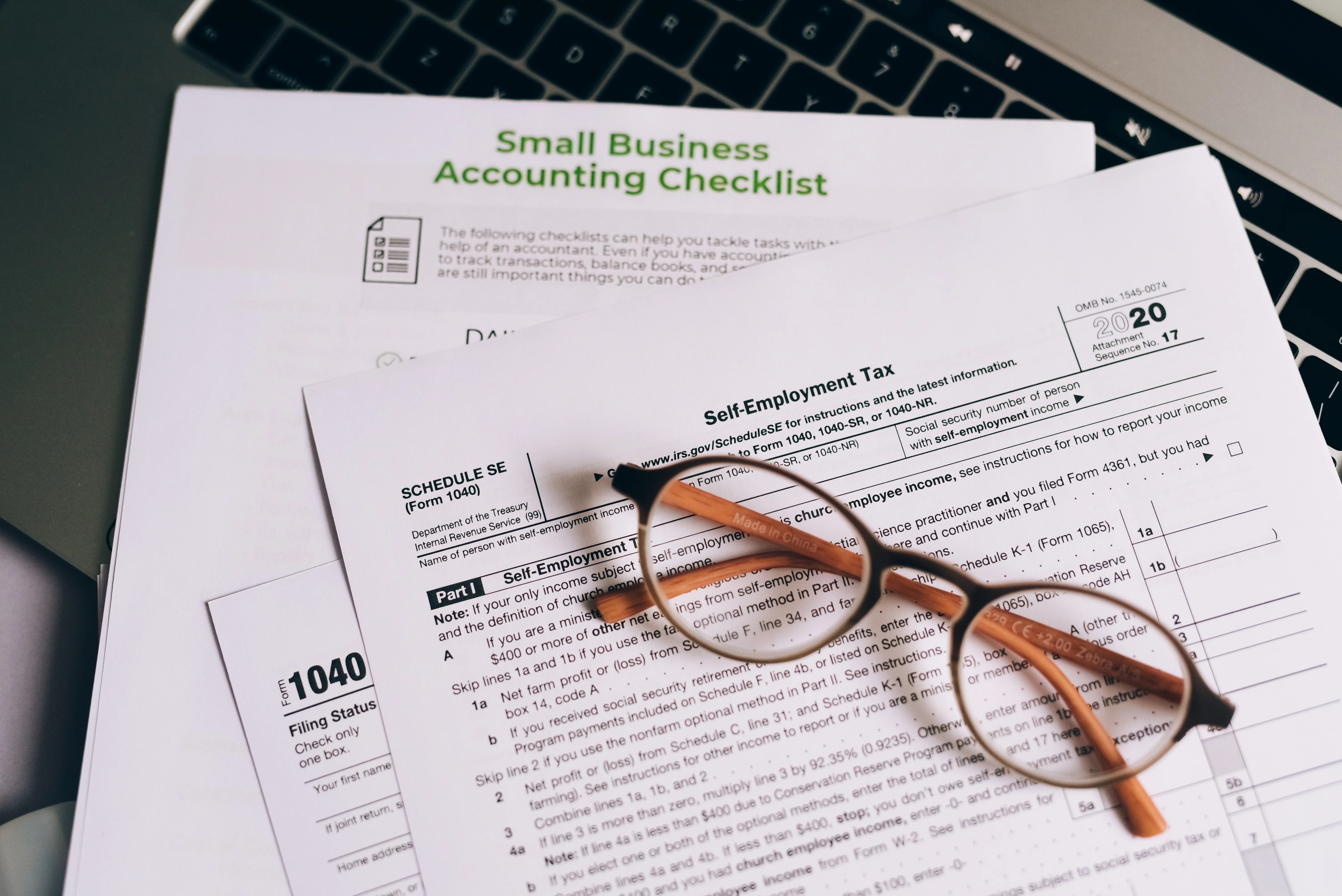 Pair of glasses resting on top of a 1040 tax form and small business checklist, learning how to rank in ai search.